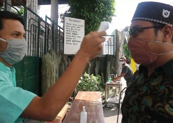 Petugas melakukan pengecekan suhu tubuh kepada tamu sebelum memasuki area pesantren Wali Barokah Kediri, sebagai bagian dari penerapan protokol kesehatan. Foto: Dok. PPWB