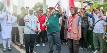 Gubernur Khofifah kiri memberikan bendera merah putih pada pimpinan organisasi kemasyarakatan salah satunya pada Ketua DPW LDII Jawa Timur KH Moch Amrodji Konawi Dok LINES