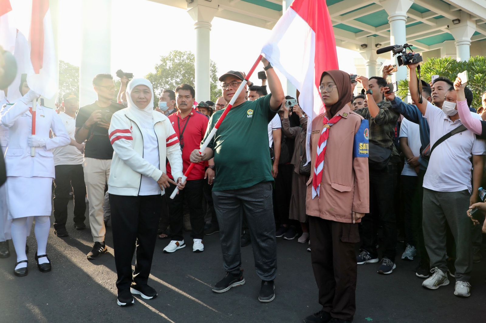 Gubernur Khofifah (kiri) memberikan bendera merah putih pada pimpinan organisasi kemasyarakatan, salah satunya pada Ketua DPW LDII Jawa Timur KH Moch Amrodji Konawi. Dok: LINES.