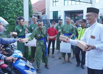 Ketua PC LDII Kecamatan Gunung Anyar, Giyato (kanan) bagikan takjil pada pengendara di kawasan jalan raya Ir Soekarno (MERR) Surabaya, Minggu (24/3). Dok: LINES.