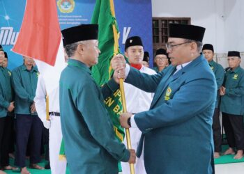 Sunaryo Abdullah menerima bendera pataka LDII Bangkalan dari Amrodji Konawi, sekaligus menandai secara simbolis penyerahan tanggung jawab kepengurusan kepada pengurus baru. Dok: LINES.