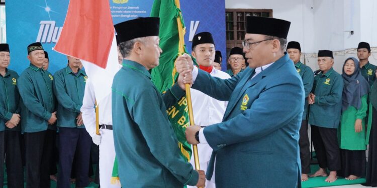 Sunaryo Abdullah menerima bendera pataka LDII Bangkalan dari Amrodji Konawi, sekaligus menandai secara simbolis penyerahan tanggung jawab kepengurusan kepada pengurus baru. Dok: LINES.