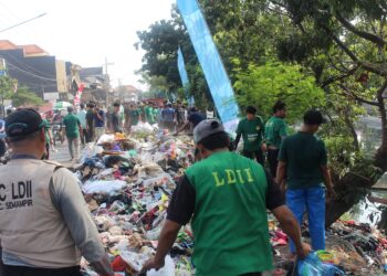 Ratusan relawan LDII membersihkan tumpukan sampah di bantaran Sungai Kali Tebu, Kenjeran, Surabaya, Minggu (10/8), dalam kerja bakti massal menyambut HUT ke-80 RI. Dok: LINES.