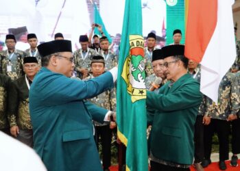 Ketua terpilih DPD LDII Kabupaten Sidoarjo masa bakti 2025–2030, M. Fauzan (kanan), menerima bendera pataka organisasi dalam prosesi pelantikan usai Musyawarah Daerah (Musda) X LDII Sidoarjo di Gedung Pondok Pesantren Al-Barokah, Sruni, Minggu (26/10). (Dok. LINES Sidoarjo)