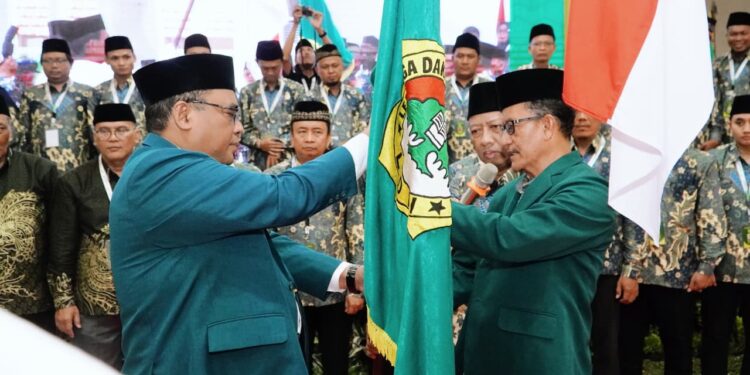 Ketua terpilih DPD LDII Kabupaten Sidoarjo masa bakti 2025–2030, M. Fauzan (kanan), menerima bendera pataka organisasi dalam prosesi pelantikan usai Musyawarah Daerah (Musda) X LDII Sidoarjo di Gedung Pondok Pesantren Al-Barokah, Sruni, Minggu (26/10). (Dok. LINES Sidoarjo)