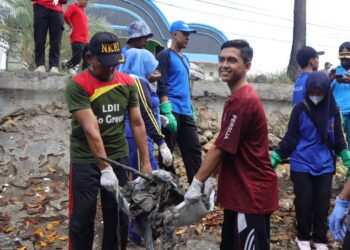 Pemuda LDII Pamekasan bersama relawan lingkungan mengangkat tumpukan sampah di kawasan Pantai Branta, Pamekasan, saat aksi bersih pantai memperingati World Clean Up Day 2025, Minggu (12/10/2025). Kegiatan ini menjadi ajang kolaborasi masyarakat dalam menjaga kebersihan dan kelestarian lingkungan. Dok. LINES.