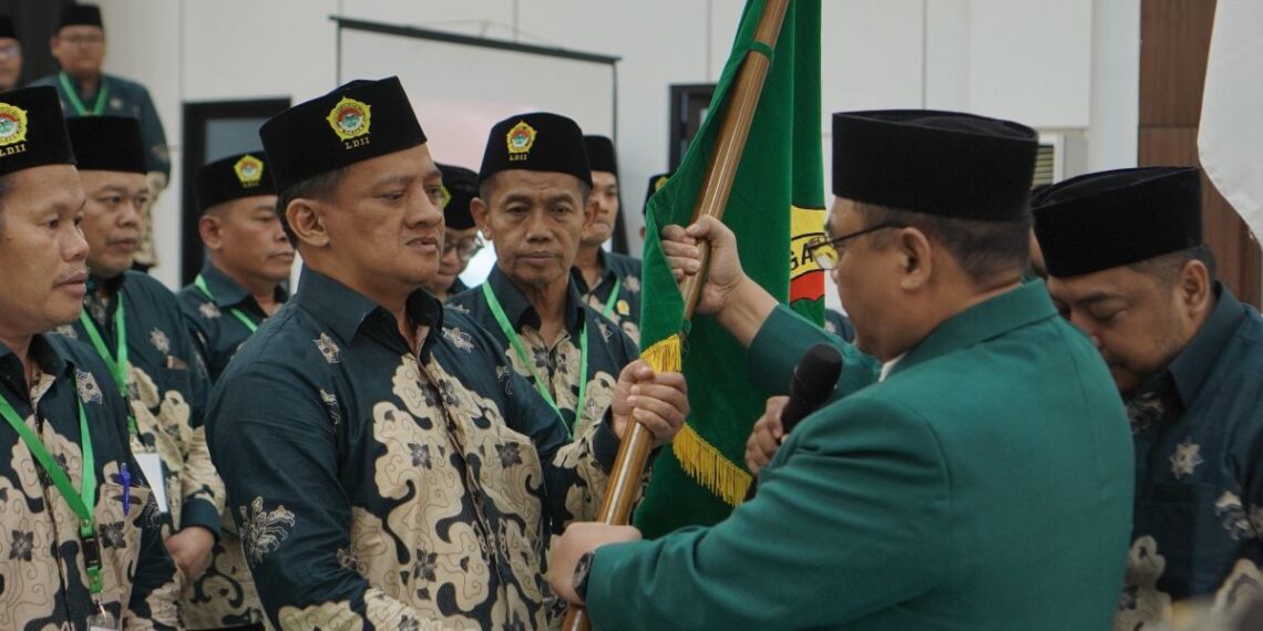 Akhmad Setiadi menerima bendera pataka sebagai tanda amanah usai terpilih kembali menjadi Ketua DPD LDII Kota Surabaya masa bakti 2025–2030, dalam Musda X LDII Kota Surabaya di Gedung Serba Guna Sabilurrosyidin, Minggu (9/11). (Foto: Dok. LINES Surabaya)