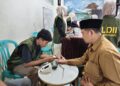 Siswa SMK Bina Sejahtera Mandiri, didampingi tenaga kesehatan, memeriksa kadar gula darah warga saat layanan kesehatan gratis yang digelar DPD LDII Banyuwangi bersama FKKI, Minggu (19/7). Foto: LINES Banyuwangi