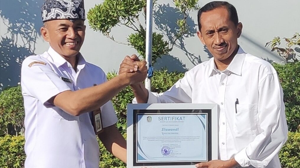 Plt Kepala Dinsos PPKB Banyuwangi Setyo Puguh Widodo menyerahkan sertifikat penghargaan kepada Siswandi di halaman Kantor Dinsos PPKB Banyuwangi Rabu 1282026 Foto LINES Banyuwangi