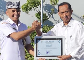 Plt Kepala Dinsos PPKB Banyuwangi Setyo Puguh Widodo menyerahkan sertifikat penghargaan kepada Siswandi di halaman Kantor Dinsos PPKB Banyuwangi Rabu 1282026 Foto LINES Banyuwangi