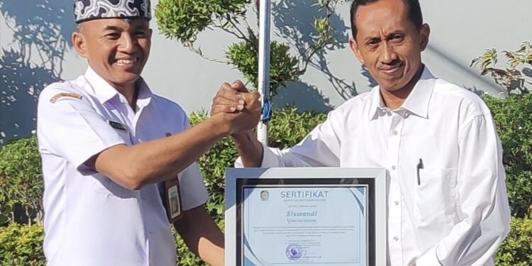 Plt Kepala Dinsos PPKB Banyuwangi Setyo Puguh Widodo menyerahkan sertifikat penghargaan kepada Siswandi di halaman Kantor Dinsos PPKB Banyuwangi Rabu 1282026 Foto LINES Banyuwangi