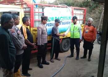 Ketua PC LDII Tulakan Suyoto menyerahkan bantuan air bersih secara simbolis kepada Kepala Dusun Wonokeso Wasito, didampingi Senkom dan personel Polsek Tulakan, Kamis (8/10/2026). Foto: LINES Pacitan